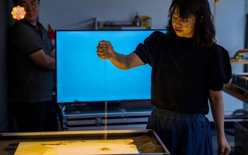 sand art instructor spraying sand